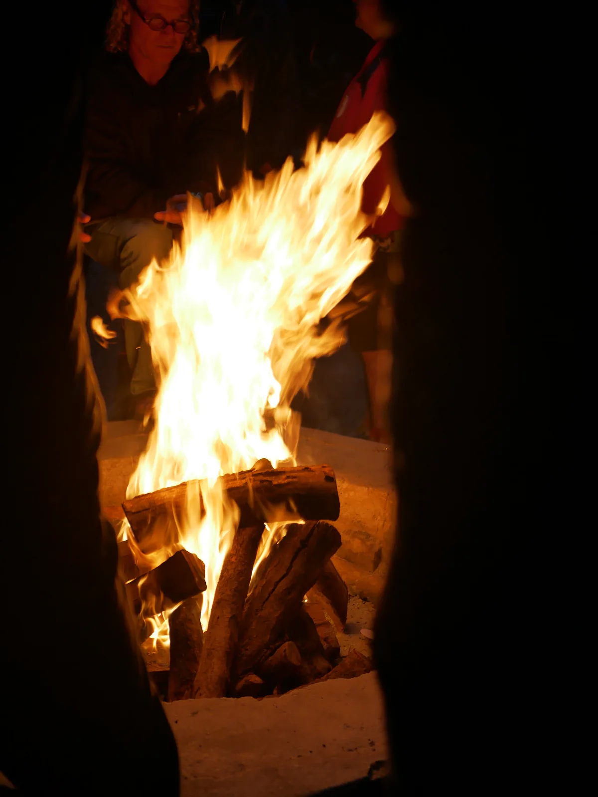 People gathered around a bright campfire at night